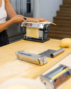 Image of Simone Agostino rolling spaghetti through a pasta machine in her workshop held from her home kitchen in Scarborough.