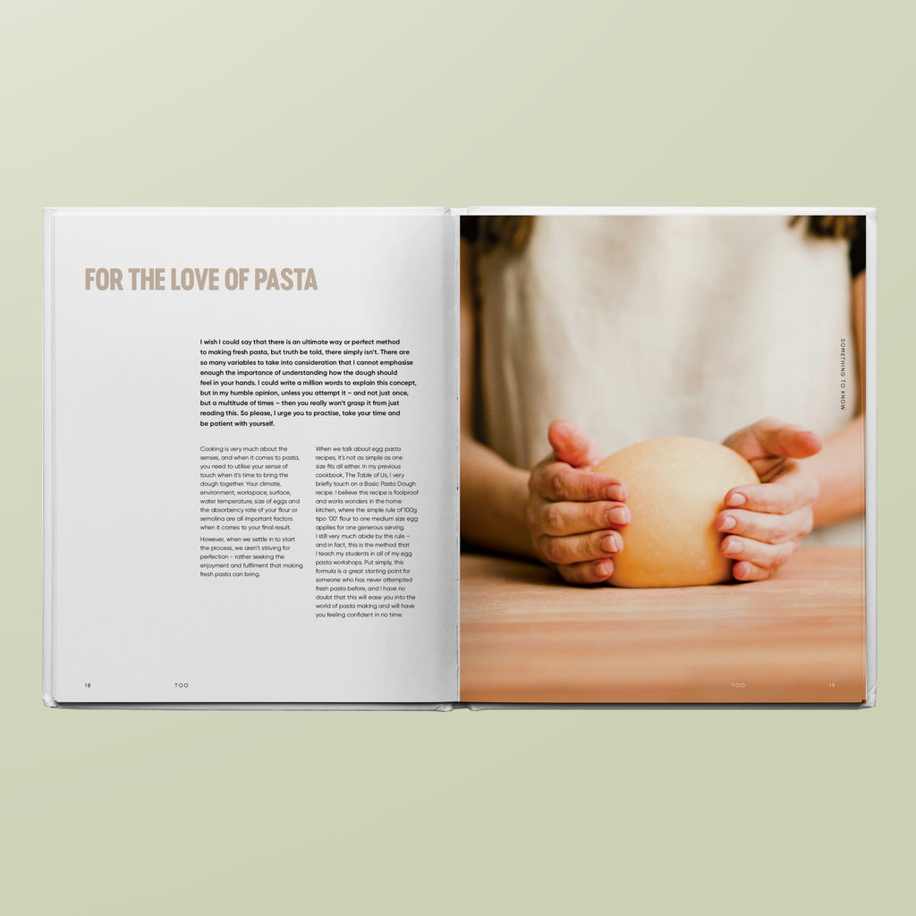 Open book with text and a photo of hands holding pasta on a light green background